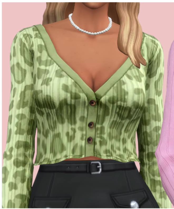 Ein blondes Sim mit abgeschnittenem Kopf vom Bild. Sie trägt eine Perlenkette mit einer grünen Leopardenmuster-Strickjacke, deren Knöpfe zugeknöpft sind.
