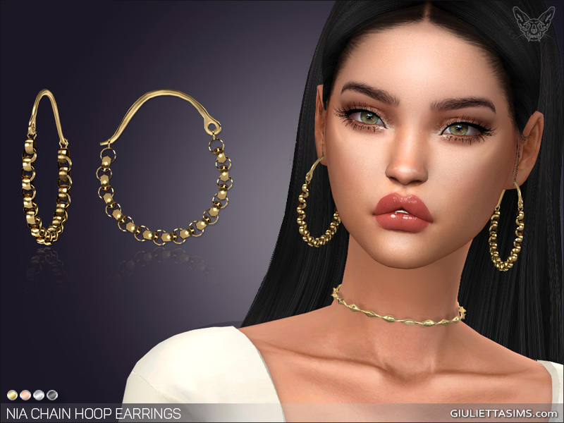 Ein Sim mit langen dunkelbraunen Haaren und grünen Augen. Sie tragen viel Lipgloss und eine goldene Halskette. Sie tragen auch ein Paar Sims 4 CC-Ohrringe, die in einem gedämpften Goldton mit Kugeln und Ketten gehalten sind.