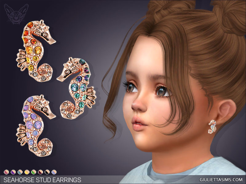 Ein Kleinkind aus Die Sims 4 mit braunen Haaren in Space Buns und braunen Augen. Sie tragen ein Paar roségoldener Steckerohrringe, die wie ein Seepferdchen aussehen und kleine Edelsteine in verschiedenen Farben enthalten.